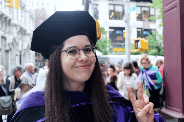 Alex's NYU LLM graduation. She is wearing a purple cap and gown.